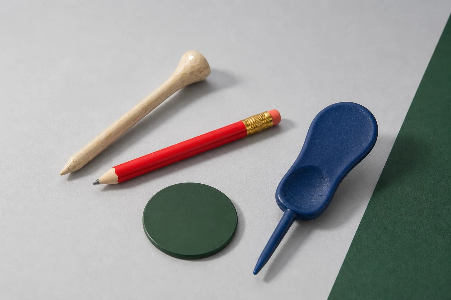Natural wood tee, red scoring pencil, green ball marker, and navy divot tool